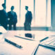 Business devices and documents at the workplace, unrecognized businesspeople sharing the ideas on the background